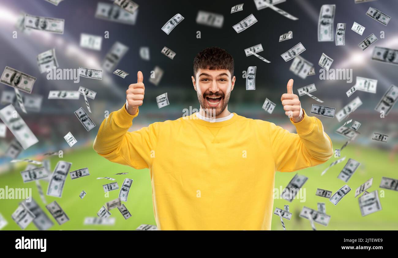 uomo felice sopra la pioggia di soldi sul campo di calcio Foto Stock