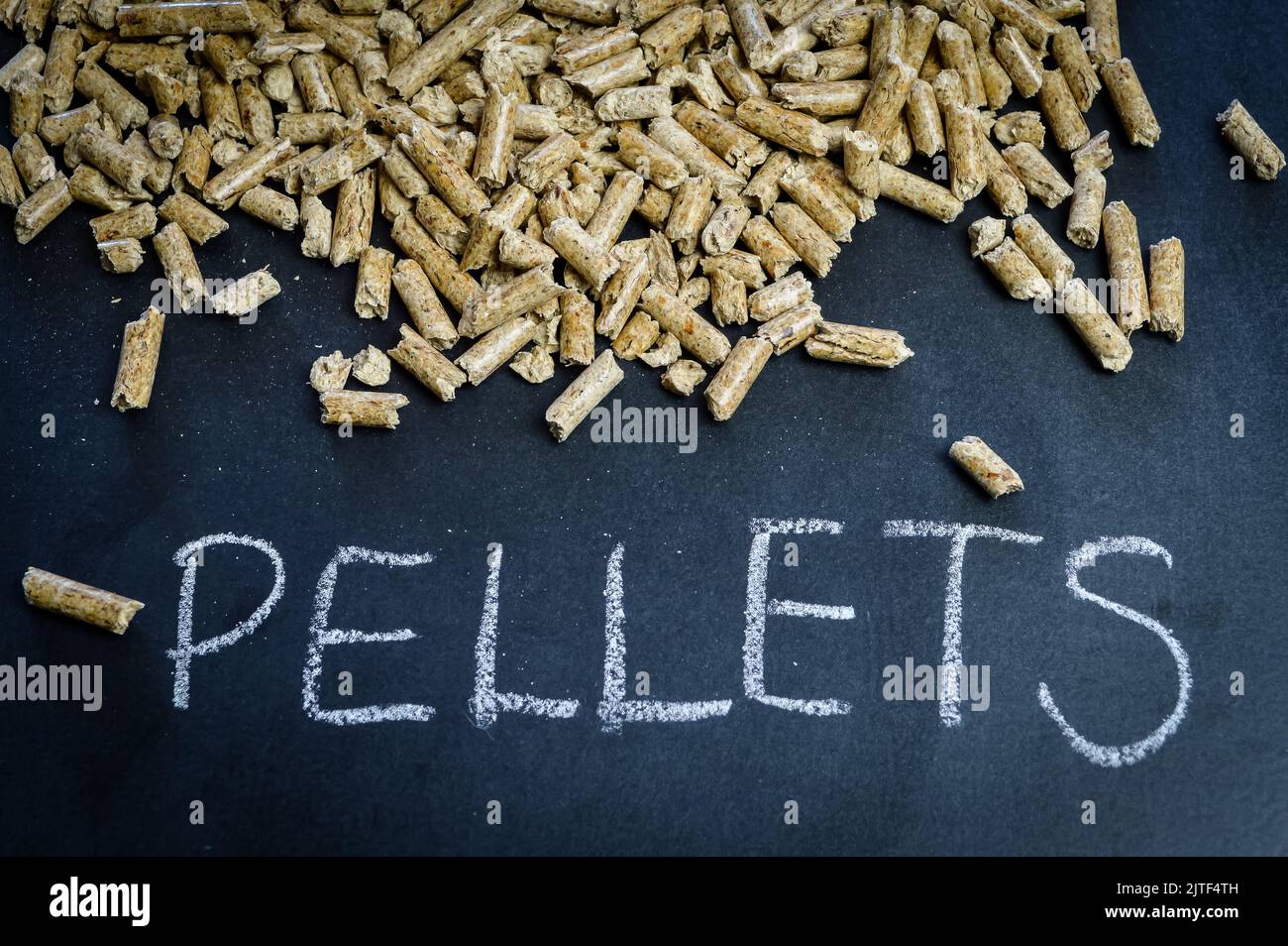 manciata di pellet di legno per il riscaldamento su una lavagna con la parola pellets manoscritta Foto Stock