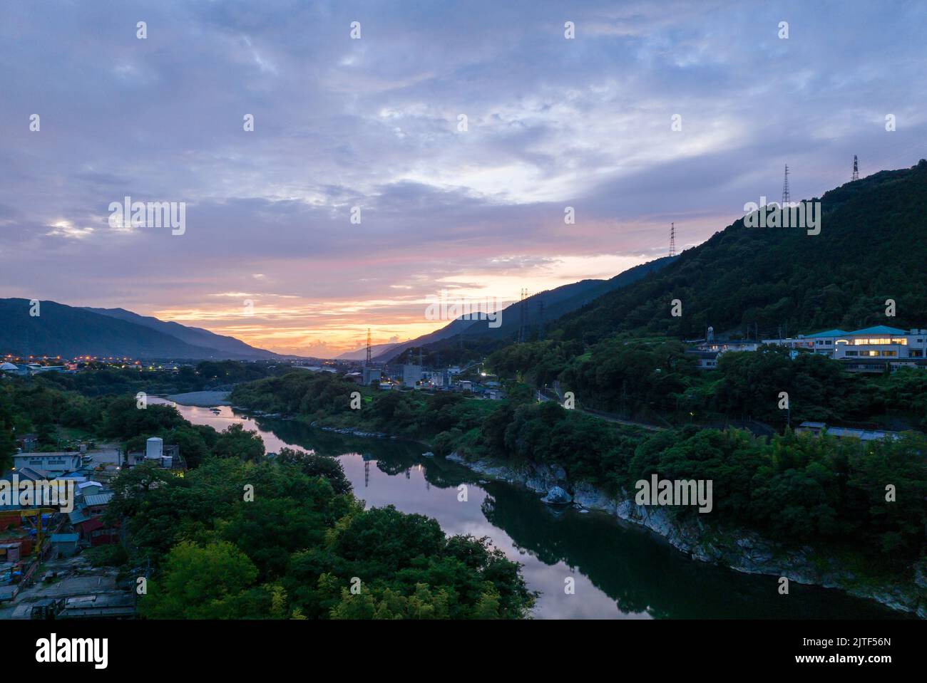 Colori dell'alba nelle nuvole sopra il fiume stretto attraverso la piccola città Foto Stock