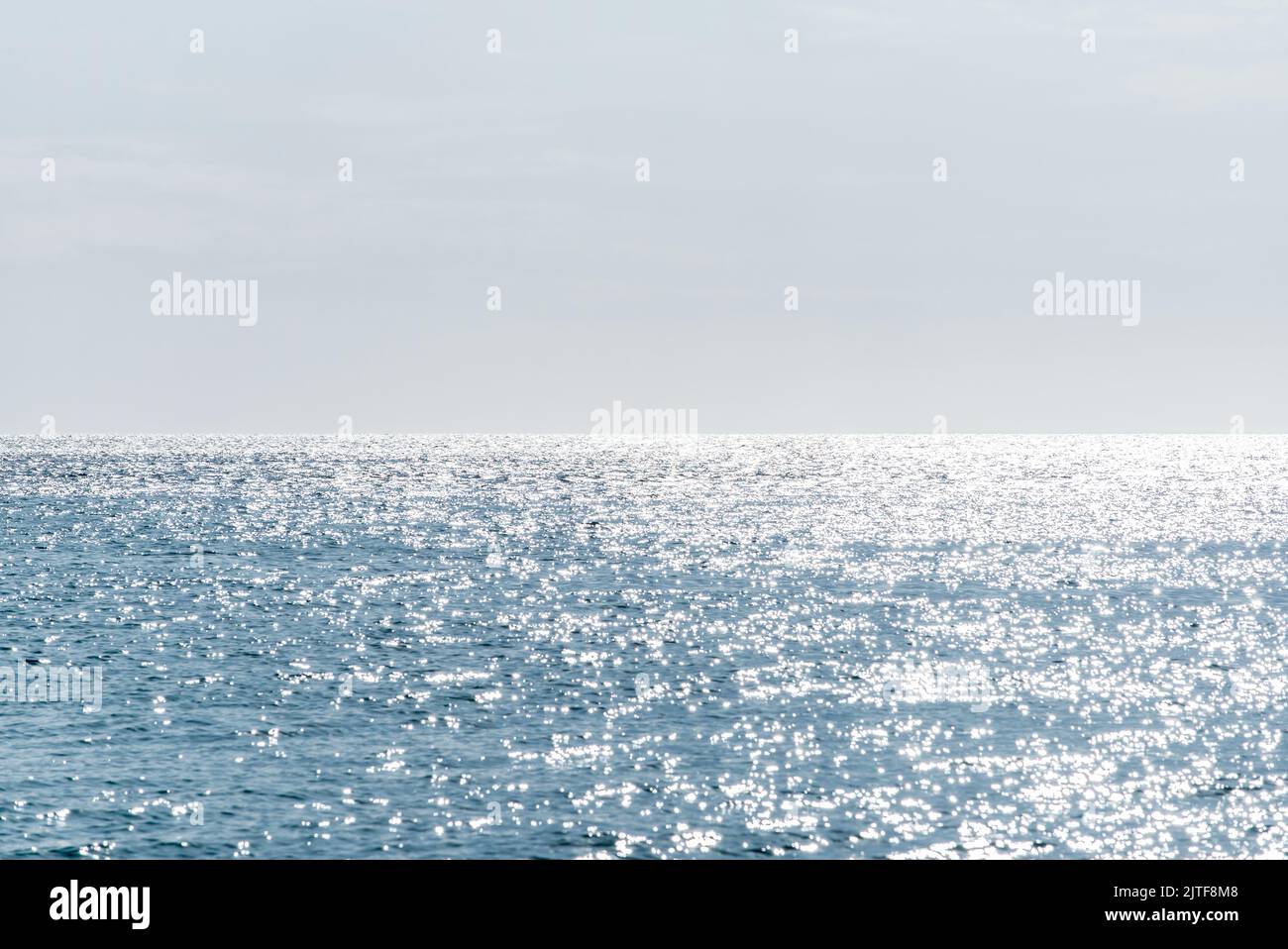 Calma superficie del mare che riflette la luce del sole Foto Stock