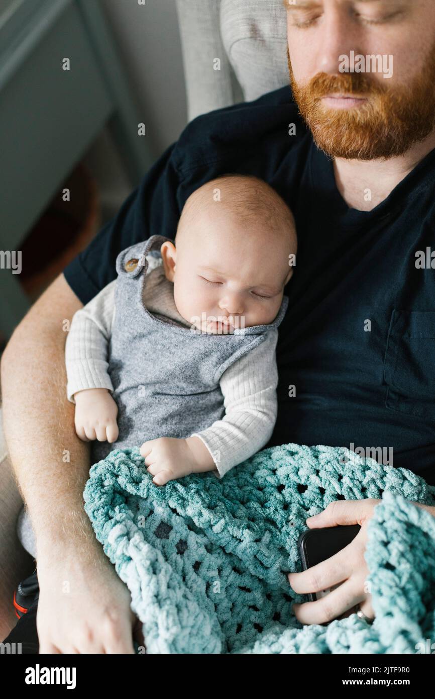 Padre che dorme con figlio neonato (0-1 mesi) Foto Stock