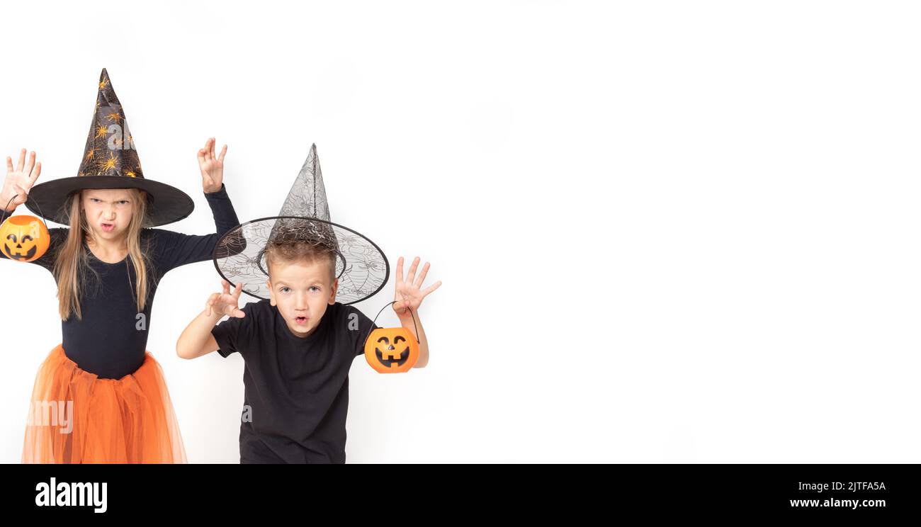 Bambini su Halloween. Una bambina e un ragazzo in costumi strega e stregone in cappelli che tengono cestini a forma di zucche facendo gesti spaventosi Foto Stock