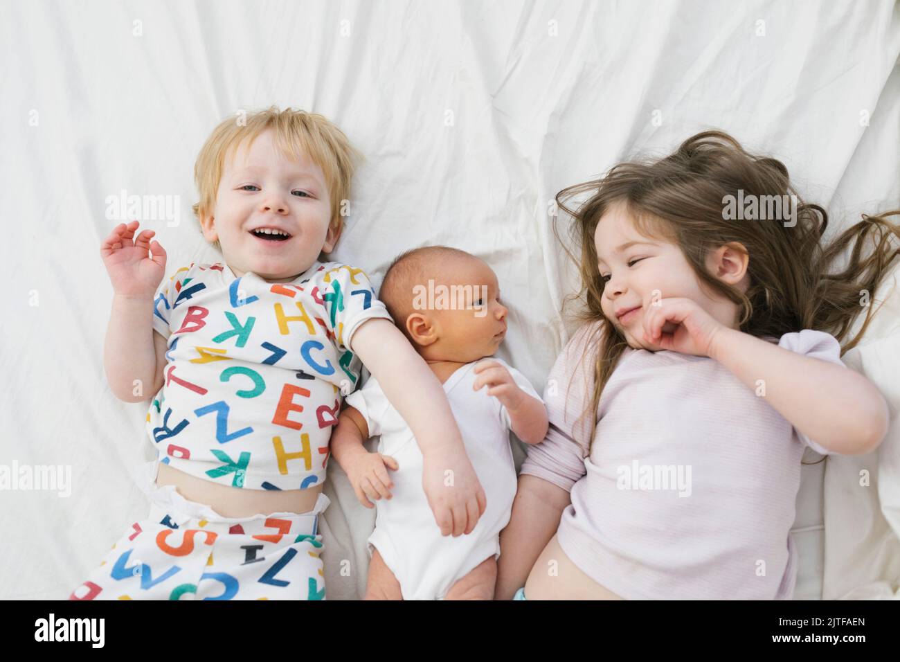 Fratelli (0-1 mesi, 2-3) sdraiati a letto Foto Stock