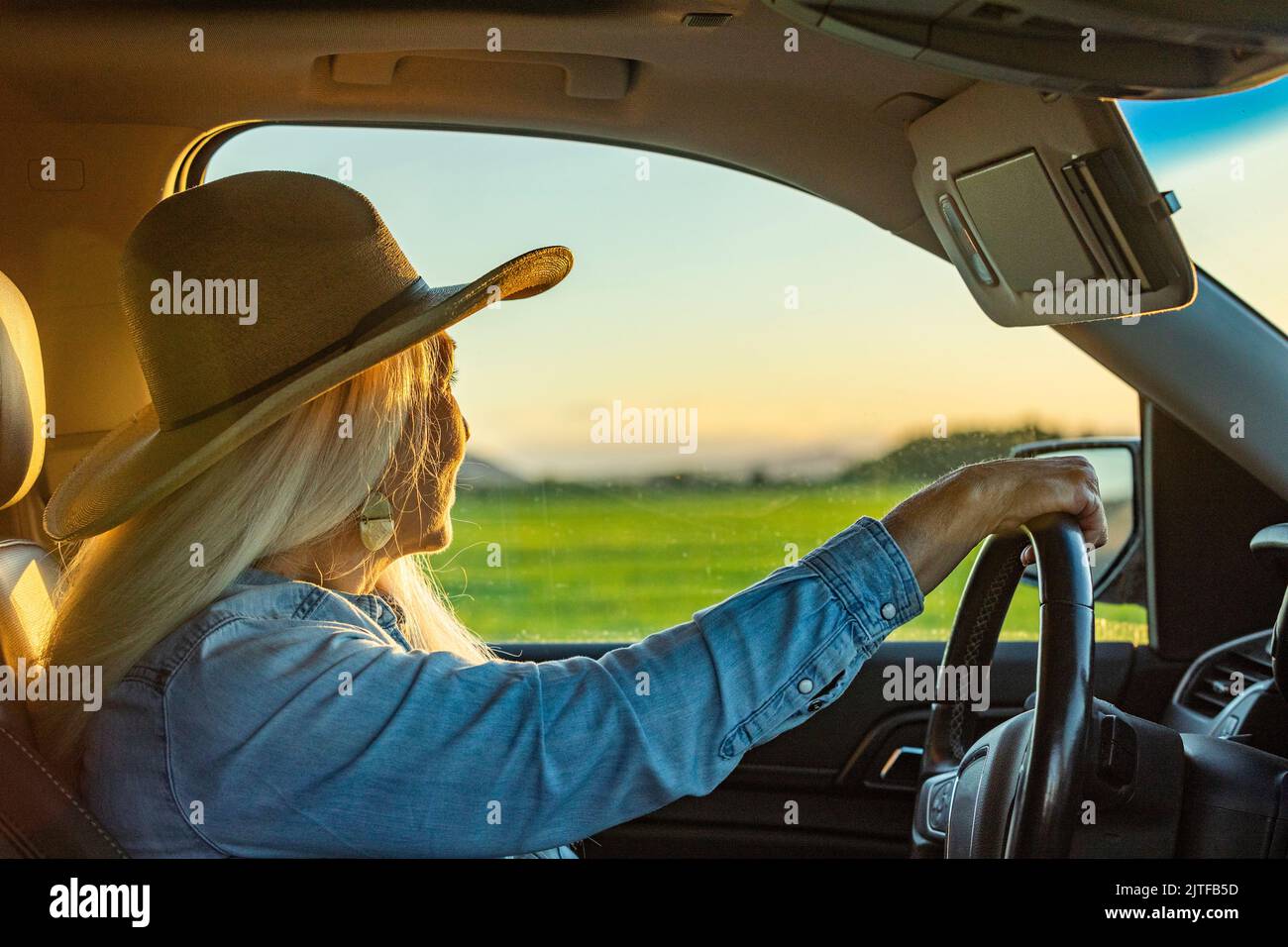 Donna bionda in auto con cappello da cowboy Foto Stock