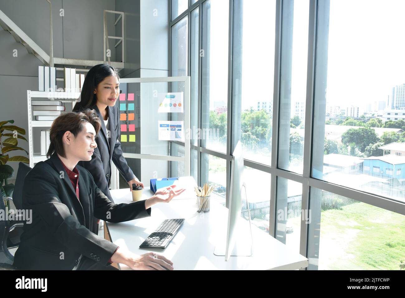 Uomo e donna asiatica d'affari che guarda lo schermo del computer portatile per discutere e lavorare in ufficio Foto Stock