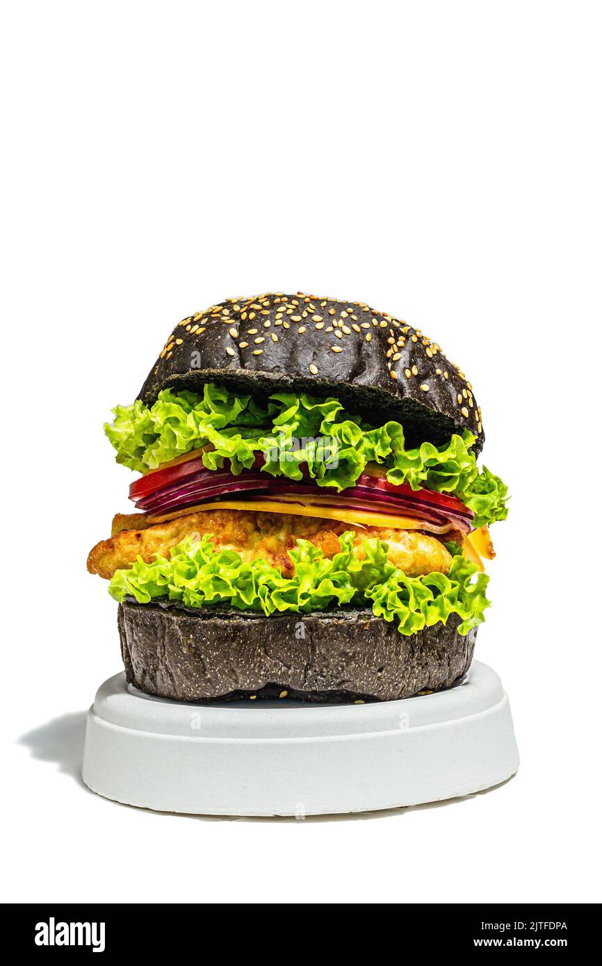 Hamburger di pesce fatto in casa con un panino nero. Ingredienti freschi, verdure mature, fast food. Moderno stand beton, luce dura alla moda, ombra scura, clos Foto Stock