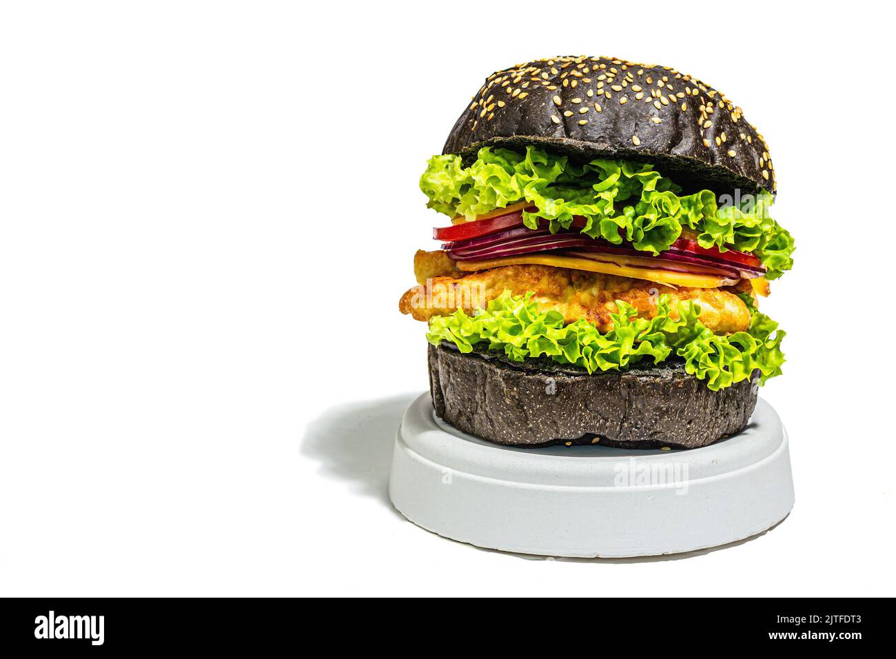 Hamburger di pesce fatto in casa con un panino nero. Ingredienti freschi, verdure mature, fast food. Moderno stand beton, luce dura alla moda, ombra scura, copia Foto Stock