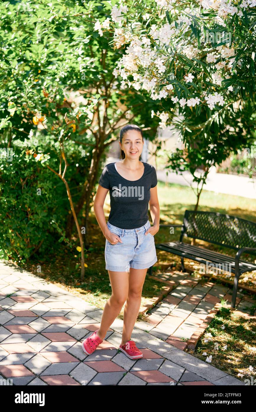 Giovane donna si trova nel parco vicino alla panchina Foto Stock