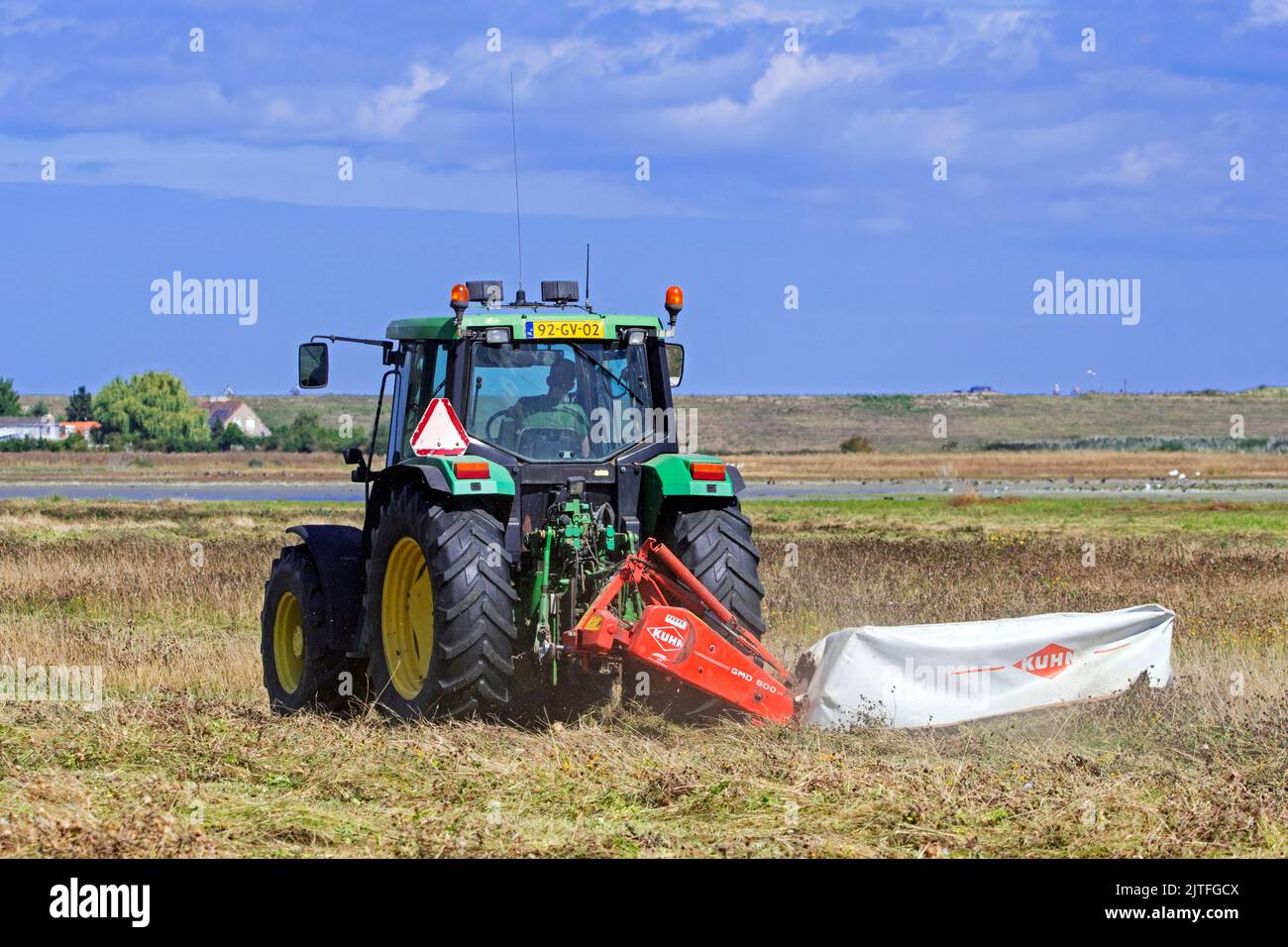 Trattore John Deere 6400 con falciatrice a disco che falcia erba in erba / prato in estate a Waterdunen, riserva naturale vicino a Breskens, Zeeland, Paesi Bassi Foto Stock