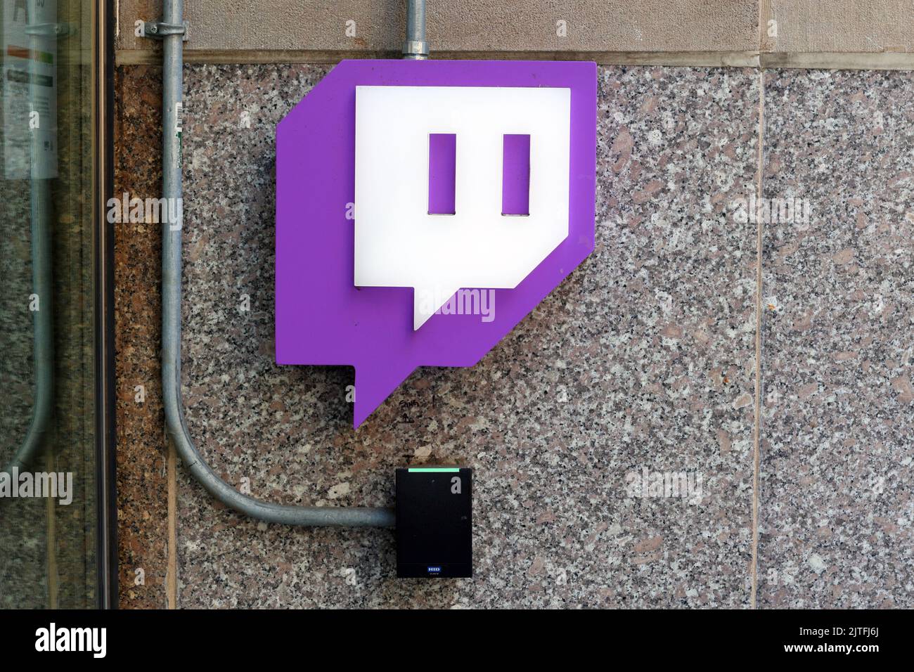 Un logo Twitch illuminato e un lettore di keycard alle porte di un edificio di New York City. Foto Stock