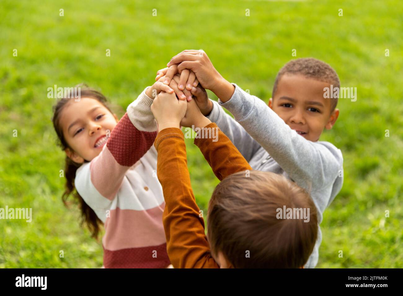 gruppo di bambini che accatastano le mani al parco Foto Stock