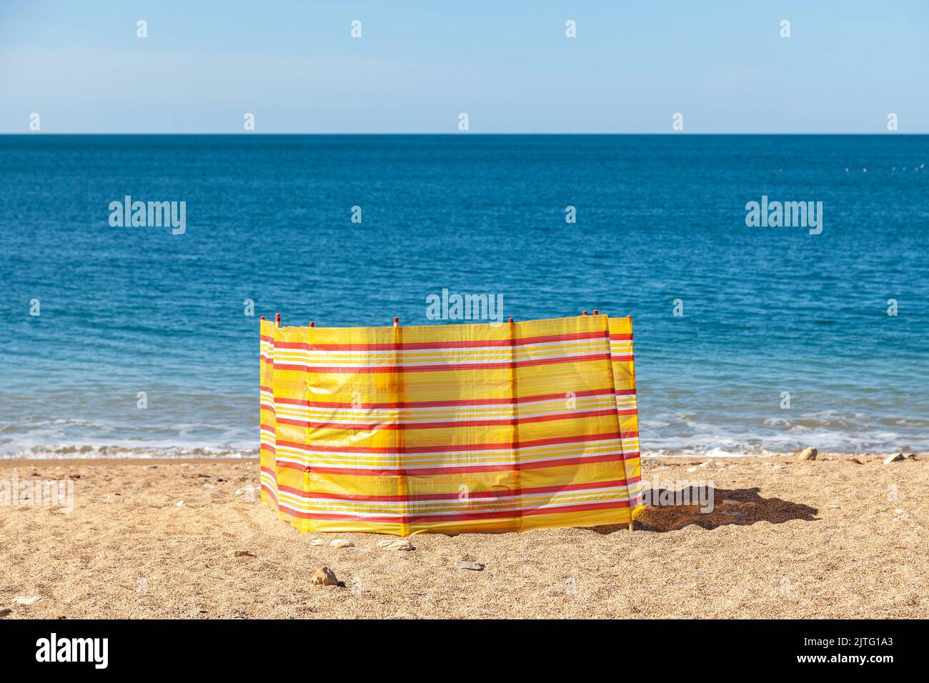 Solitario frangivento su una spiaggia di ciottoli Foto Stock