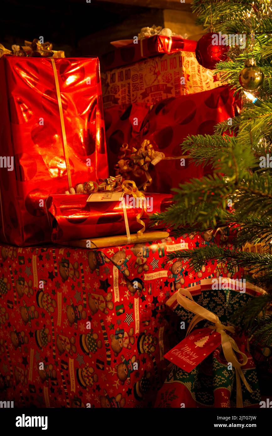 Un caldo bagliore su un pile di regali di Natale presenta accanto a un albero di Natale Foto Stock