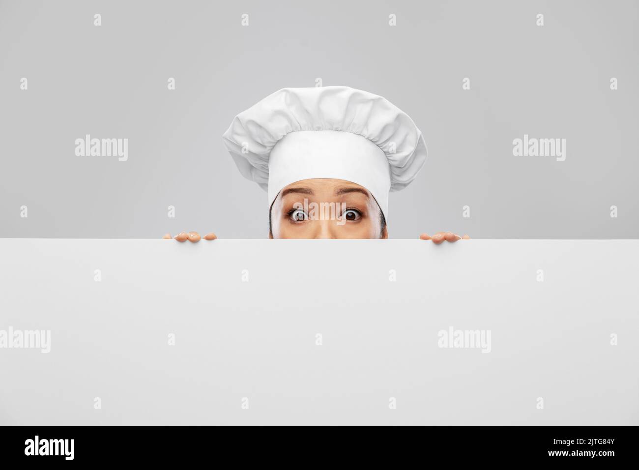 chef femminile che si scopano da dietro la lavagna bianca Foto Stock