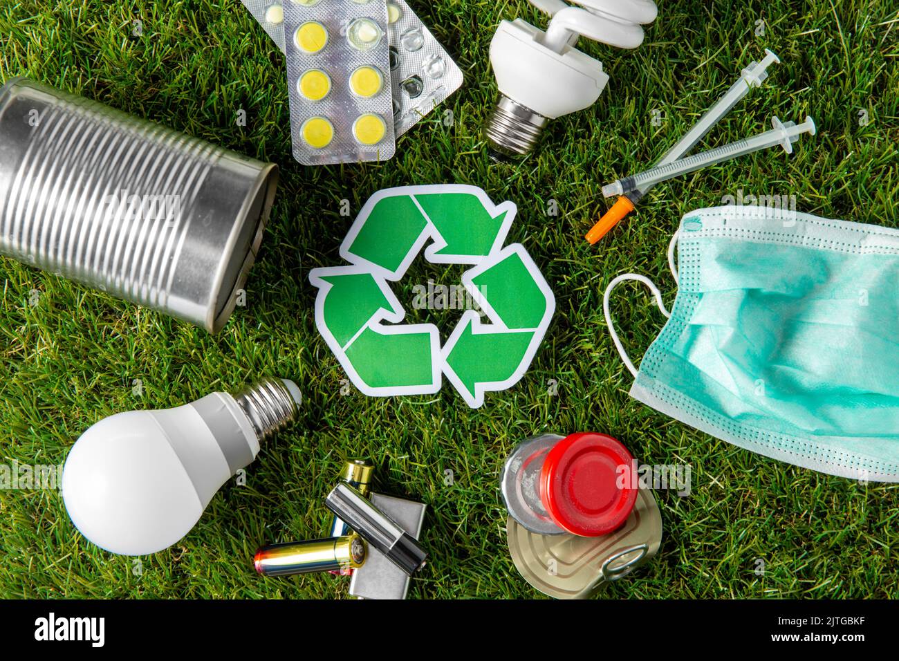 cartello verde di riciclaggio con i rifiuti domestici sull'erba Foto Stock
