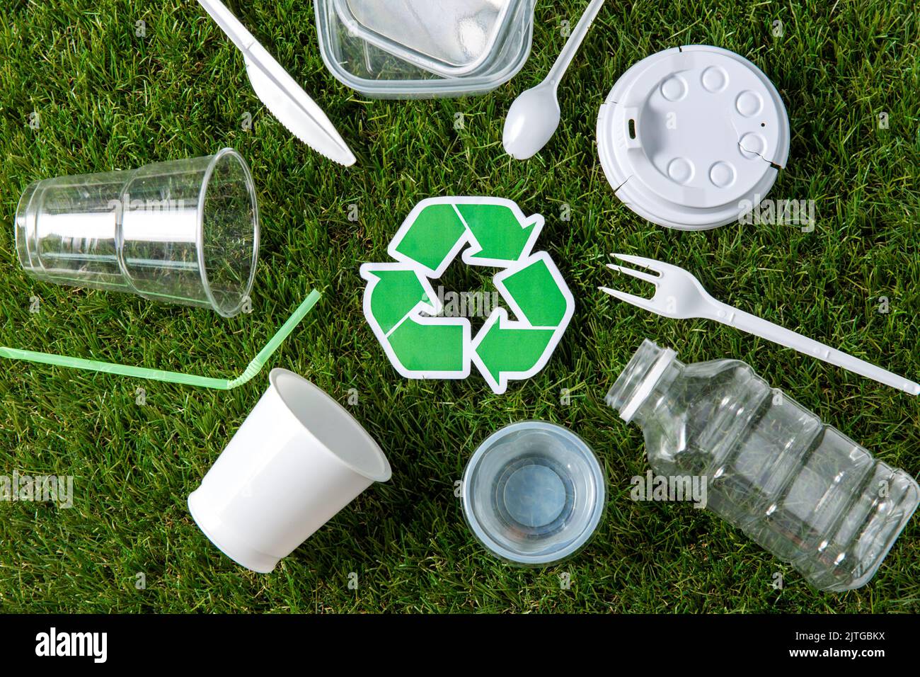 cartello verde di riciclaggio e rifiuti di plastica su erba Foto Stock