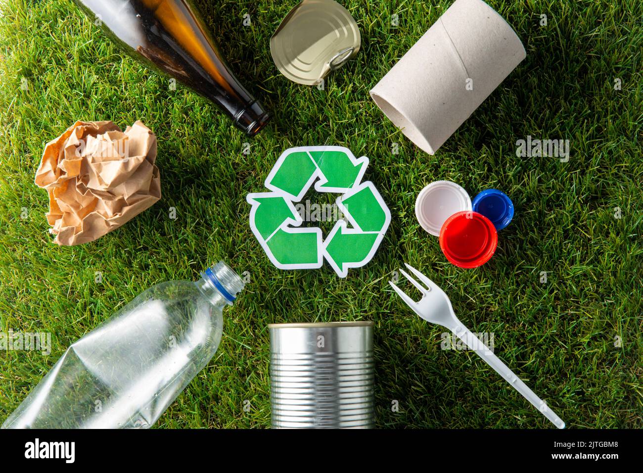 cartello verde di riciclaggio con i rifiuti domestici sull'erba Foto Stock