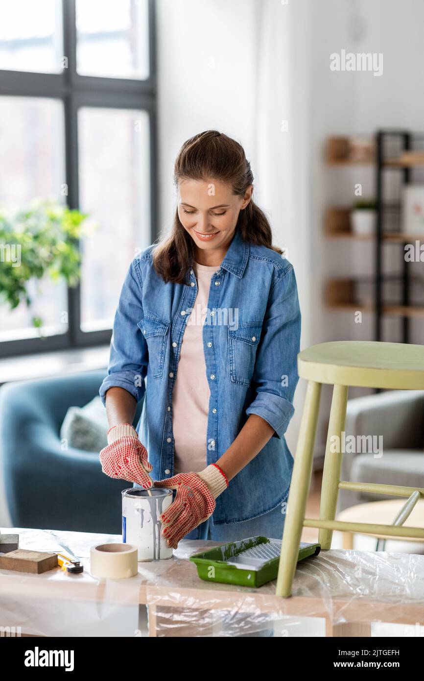 felice donna sorridente che rinnova la vecchia sedia a casa Foto Stock