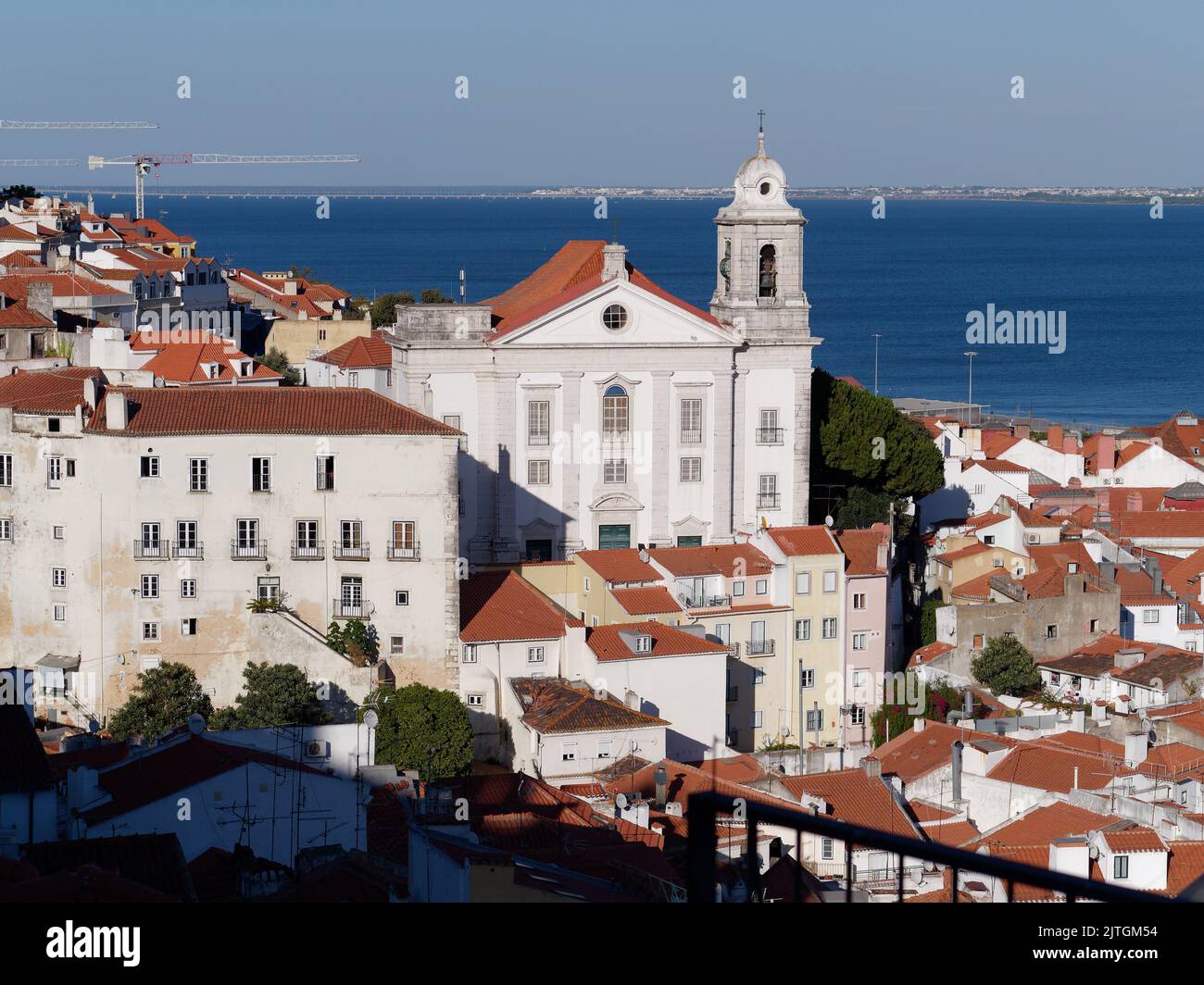 Vista dal punto panoramico Miradouro Portas do Sol a Lisbona, Portogallo, in una serata estiva con una chiesa e il campanile e il fiume Tago dietro. Foto Stock