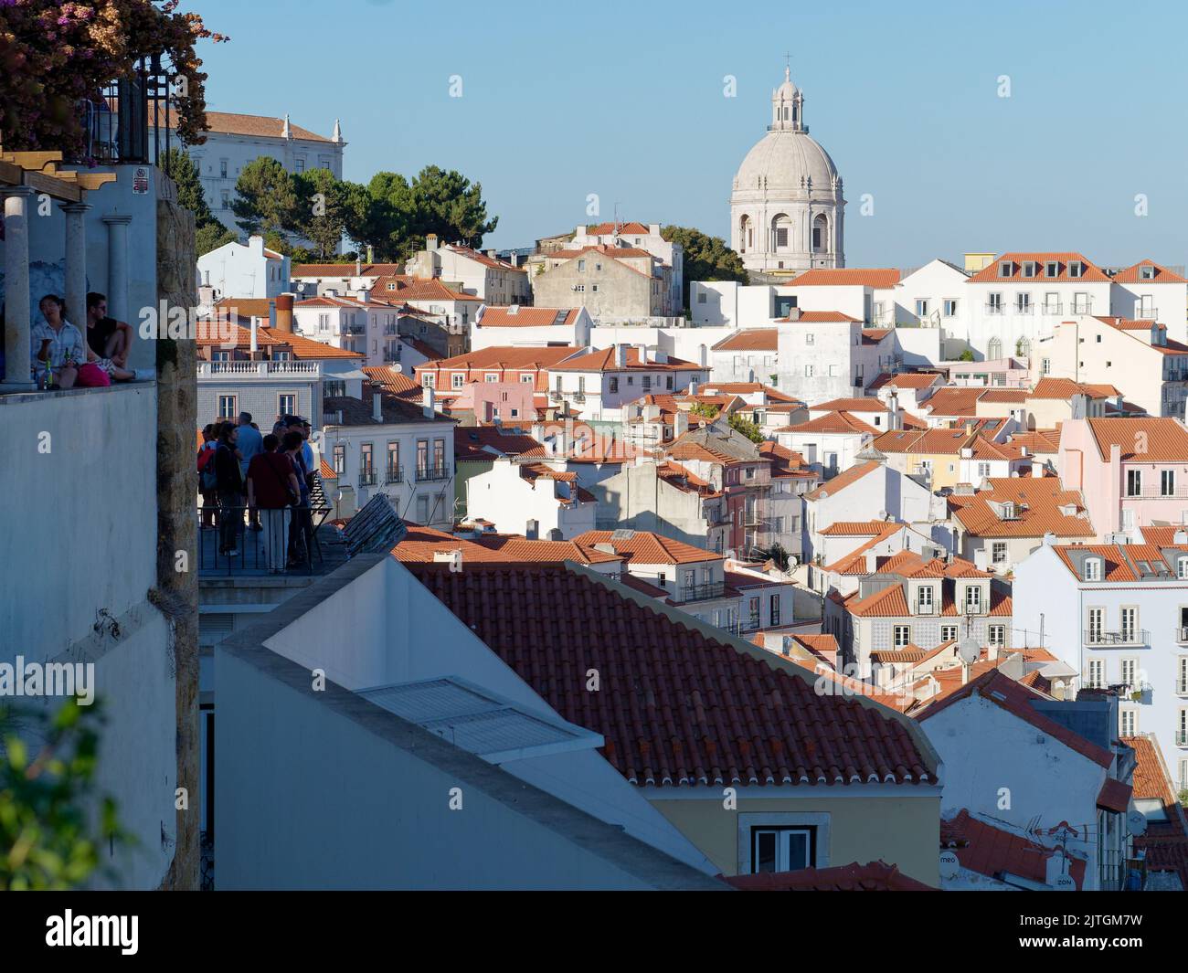 Punto di osservazione Miradouro de Santa Luzia a Lisbona, Portogallo, attraverso i tetti della città, mentre i turisti godono la vista in una serata estiva. Foto Stock