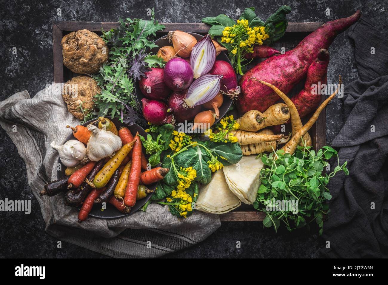 Scatola di legno traboccante di verdure fresche della fattoria, con tovagliolo rustico Foto Stock