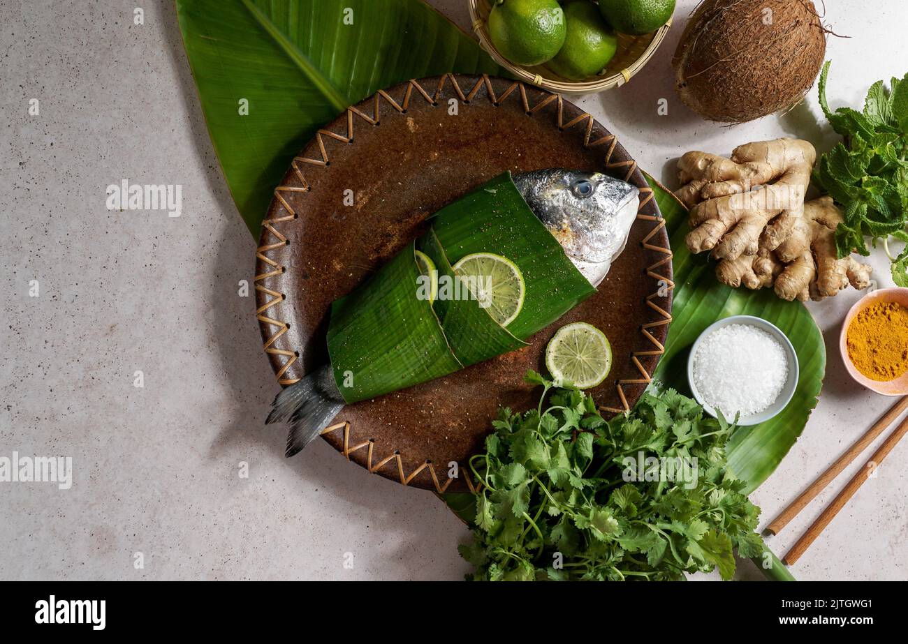 Pesce fresco in foglie di banana in stile tailandese con zenzero e lime. Cucina asiatica. Vista dall'alto Foto Stock