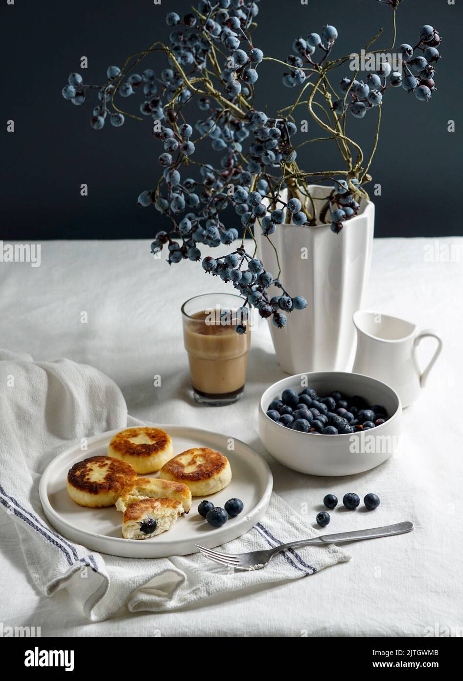 Syrniki con mirtilli e caffè. Colazione gustosa. Frittelle fritte di quark (formaggio cagliato); Foto Stock
