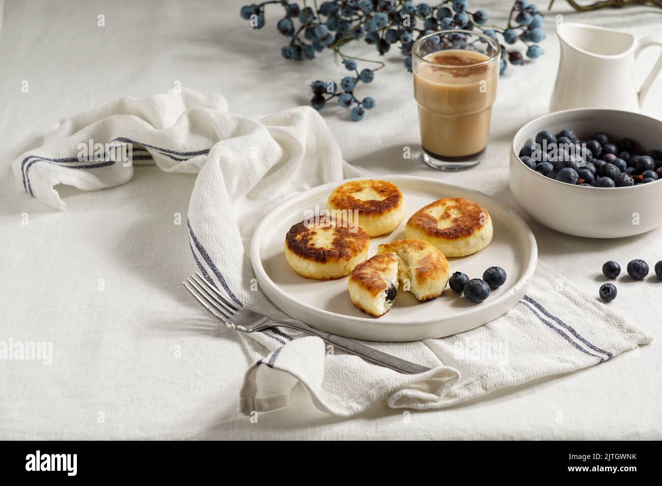 Syrniki con mirtilli e caffè. Colazione gustosa. Frittelle fritte di quark (formaggio cagliato); Foto Stock