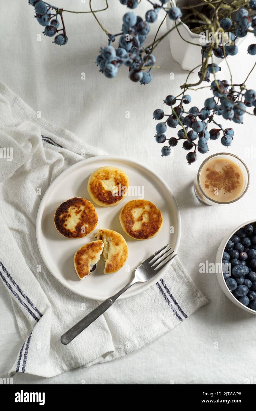 Syrniki con mirtilli e caffè. Colazione gustosa. Frittelle fritte di quark (formaggio cagliato); Foto Stock