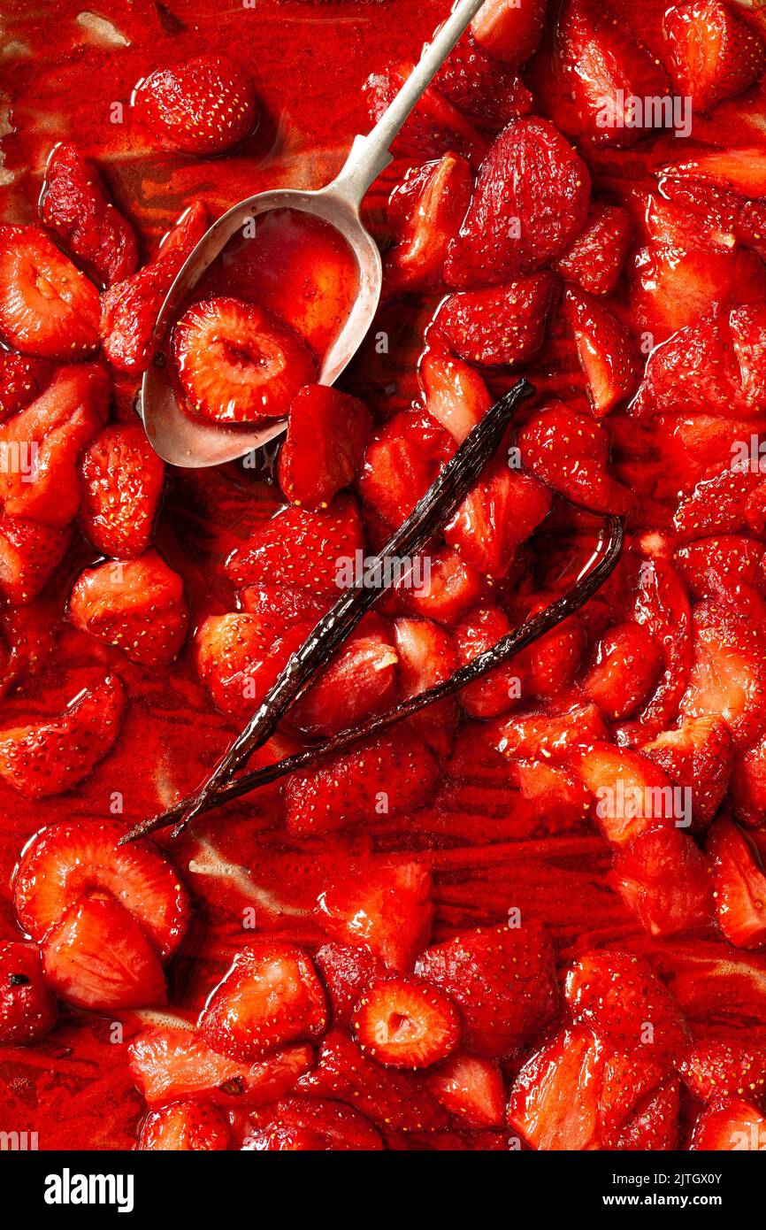 Salsa di fragole su una teglia da tostatura con baccello di vaniglia e un cucchiaio. Foto Stock