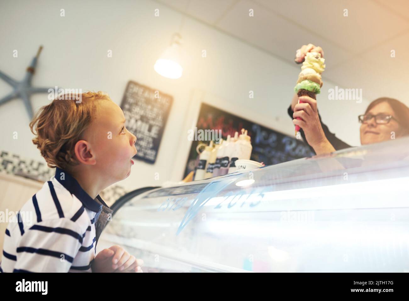 Le palline di felicità si accatastano, un ragazzo che attende con impazienza il cono gelato. Foto Stock