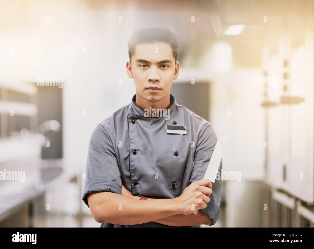 Im ritagliato per questo. Ritratto corto di un giovane chef maschio in piedi con un coltello in cucina. Foto Stock