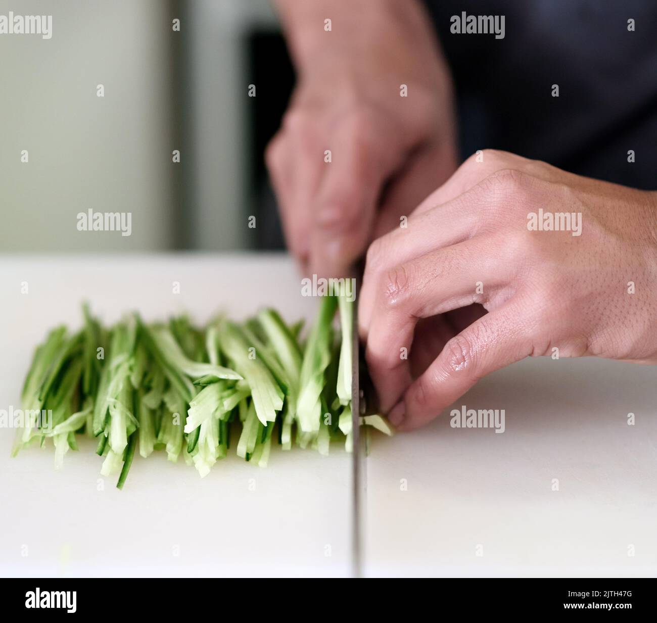 Mani stabili richiedevano. Un giovane uomo non identificabile affettando le verdure nella sua cucina. Foto Stock