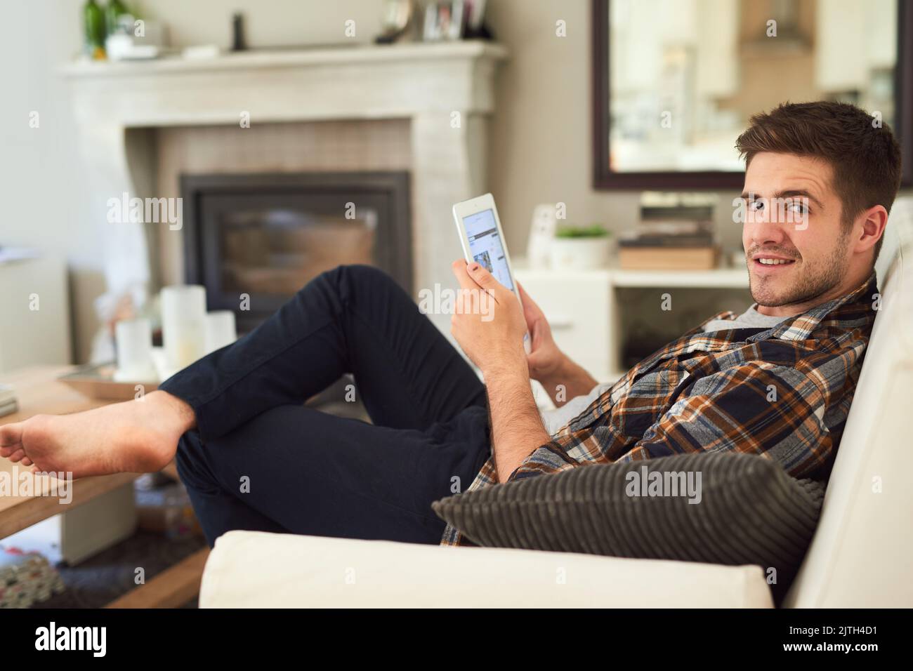 L'intrattenimento del weekend è stato risolto grazie a questo piccolo e pratico gadget. Un giovane uomo che si rilassa a casa con il suo tablet digitale. Foto Stock