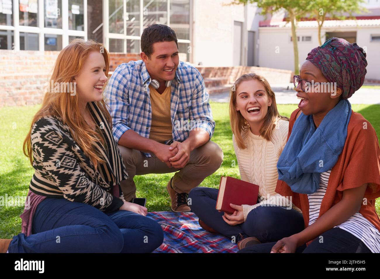 Anche durante le loro pause hanno tempo per studiare. Un gruppo di giovani amici che hanno la loro sessione di studio fuori. Foto Stock