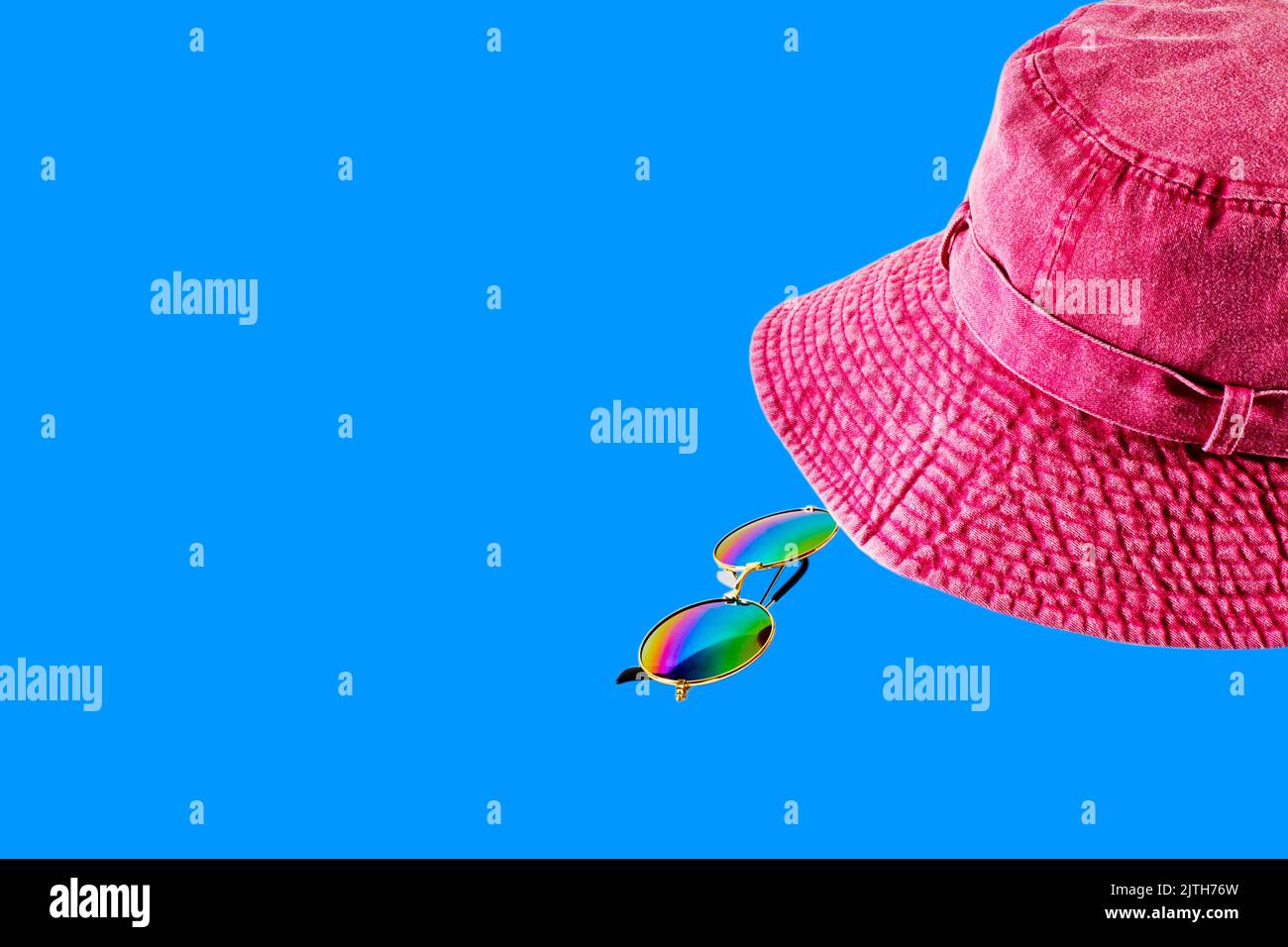 Un cappello rosso rosa con occhiali da sole isolati su sfondo colorato Foto Stock