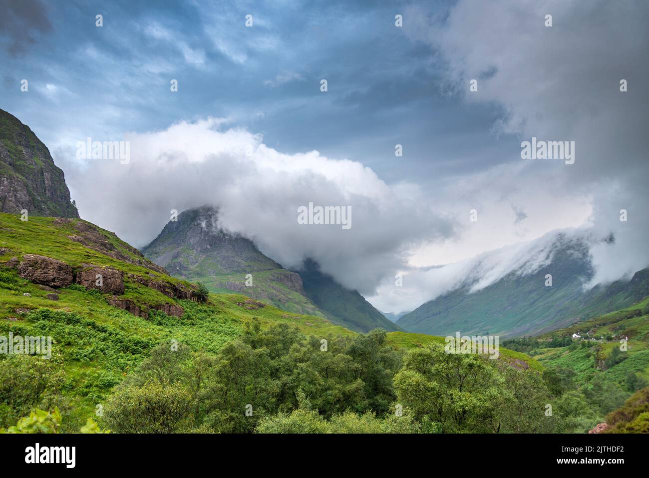 Le nuvole del tramonto del primo pomeriggio rotolano rapidamente, lungo la bella valle verde, durante l'estate, un lontano cottage bianco all'interno delle terre drammatiche Foto Stock