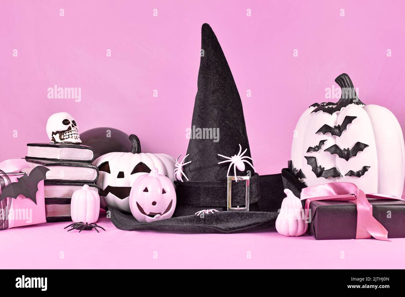 Decorazioni di Halloween rosa con zucche bianche e nere, cappello di strega, libri di incantesimi, regali e ragni Foto Stock