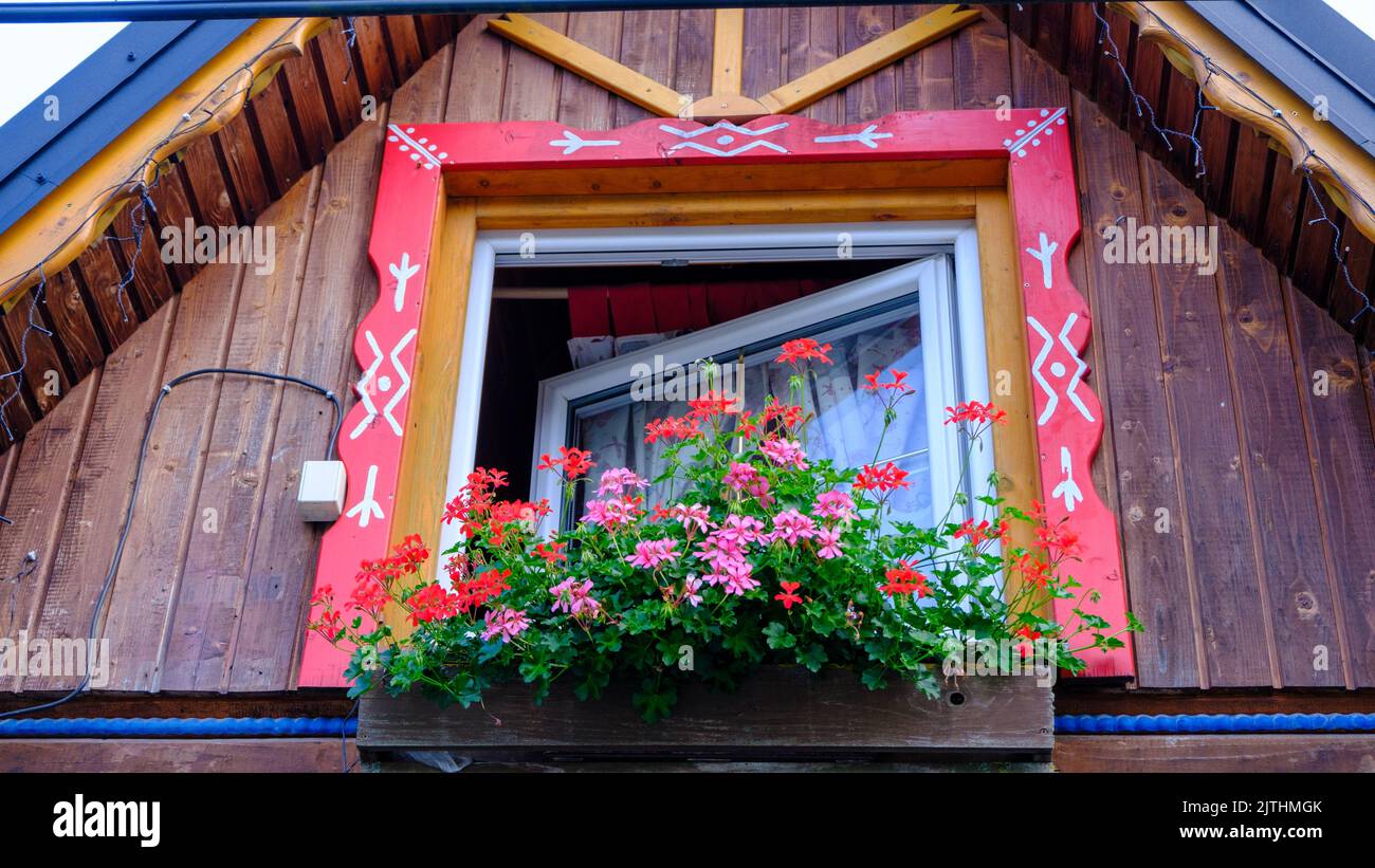 Elemento decorativo di una vecchia casa in legno. Telaio finestra in legno rosso. Simboli nazionali della Slovacchia. Foto Stock