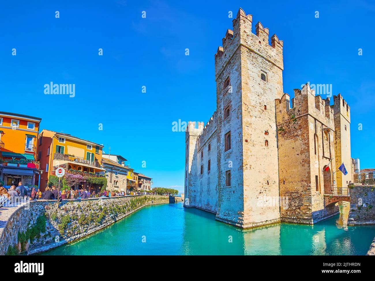 SIRMIONE, ITALIA - 10 APRILE 2022: Il principale punto di riferimento storico di Sirmione - Castello Scaligero con fossato e case colorate intorno a Via Dante Foto Stock