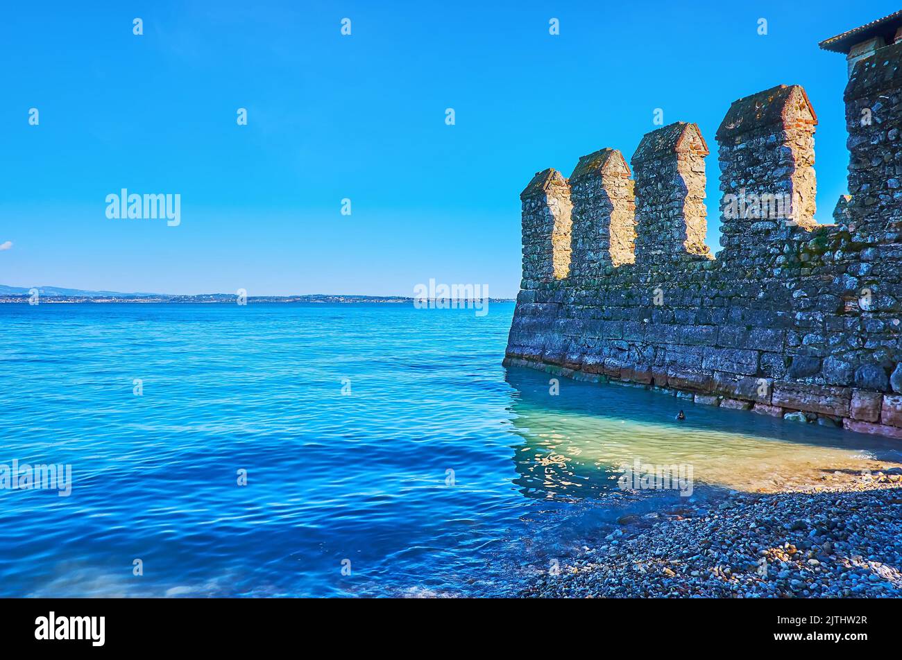 L'azzurro del lago di Garda con le mura medievali conservate del Castello Scaligero, Sirmione, Italia Foto Stock