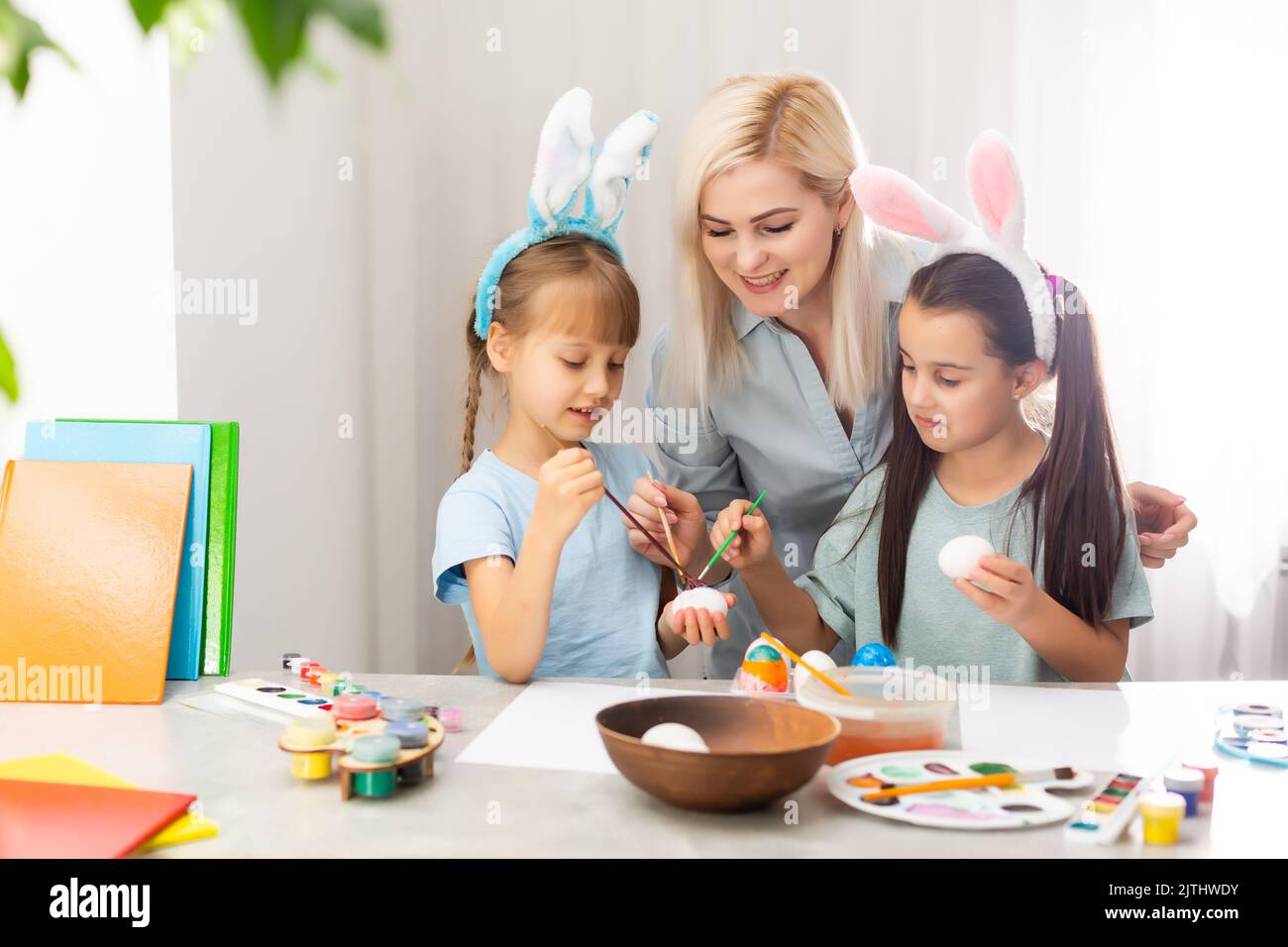 Giovane madre e le sue due figlie di pittura delle uova di Pasqua Foto Stock