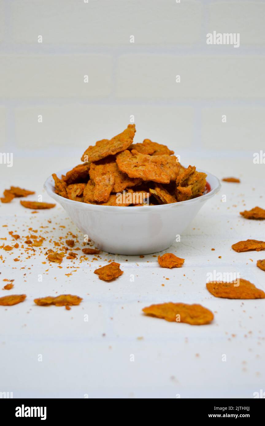 Patatine di tempeh gustose e deliziose in una ciotola con fondo bianco. Vuoi uno spuntino saporito e croccante? I chip tempeh sono la risposta. Foto Stock