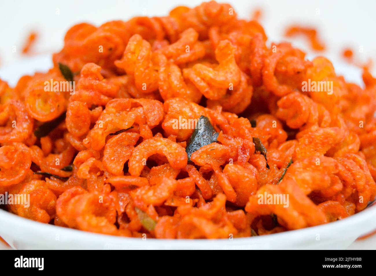 Maccheroni piccanti e saporiti in una ciotola su fondo bianco. I maccheroni secchi hanno una sensazione diversa quando vengono consumati come snack. Foto Stock