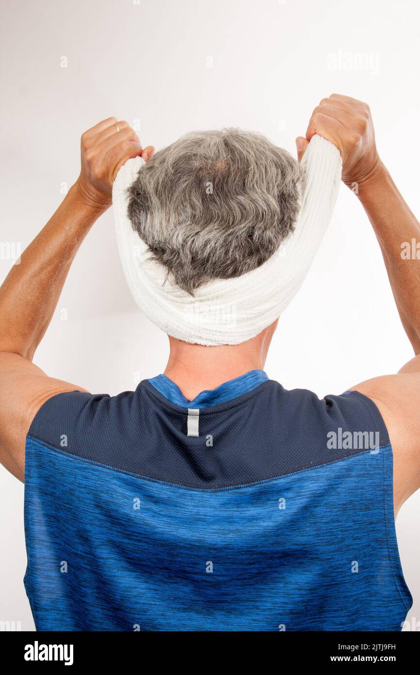 Uomo maturo 60plus allungando il collo per alleviare il dolore con un asciugamano Foto Stock