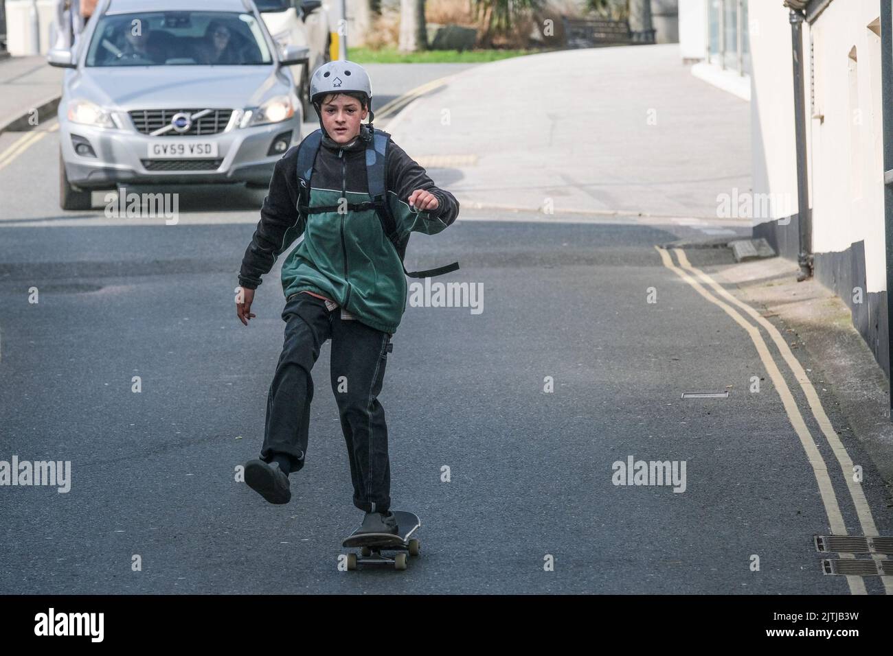 Un giovane skateboarder ignorare il traffico sulla strada principale nel centro di Newquay Town in Cornovaglia. Foto Stock