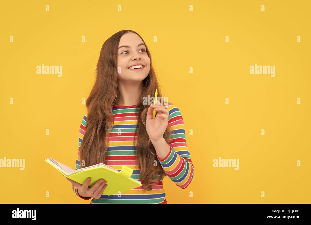 Flash di genio. La ragazza felice tiene copybook che punta la penna in su. Bambino genio sfondo giallo Foto Stock