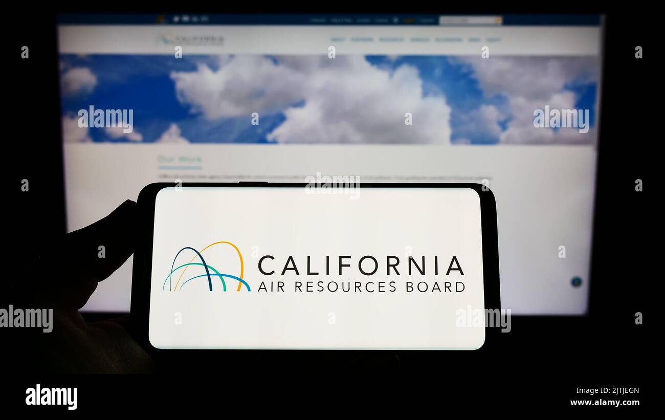 Persona che tiene in mano lo smartphone con il logo del California Air Resources Board (CARB) sullo schermo davanti al sito Web. Messa a fuoco sul display del telefono. Foto Stock