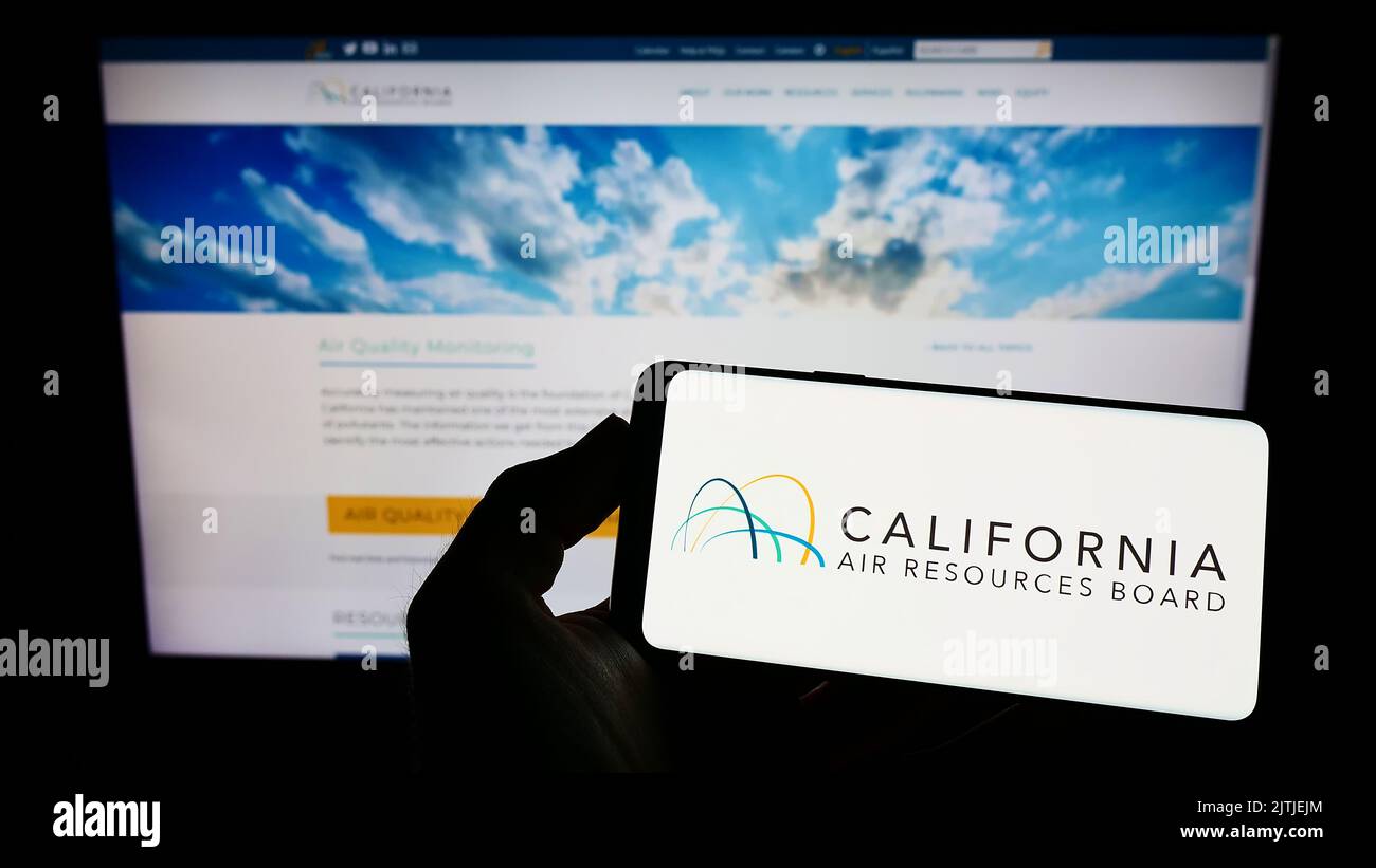 Persona che tiene un telefono cellulare con il logo del California Air Resources Board (CARB) sullo schermo davanti alla pagina Web. Messa a fuoco sul display del telefono. Foto Stock