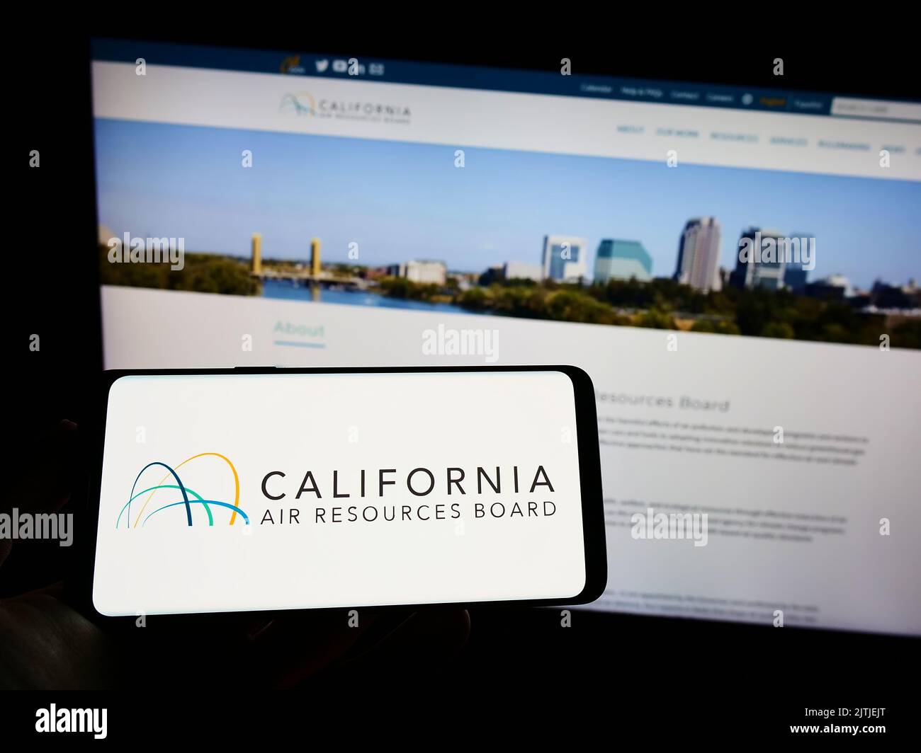 Persona che tiene il cellulare con il logo del California Air Resources Board (CARB) sullo schermo di fronte alla pagina web. Messa a fuoco sul display del telefono. Foto Stock